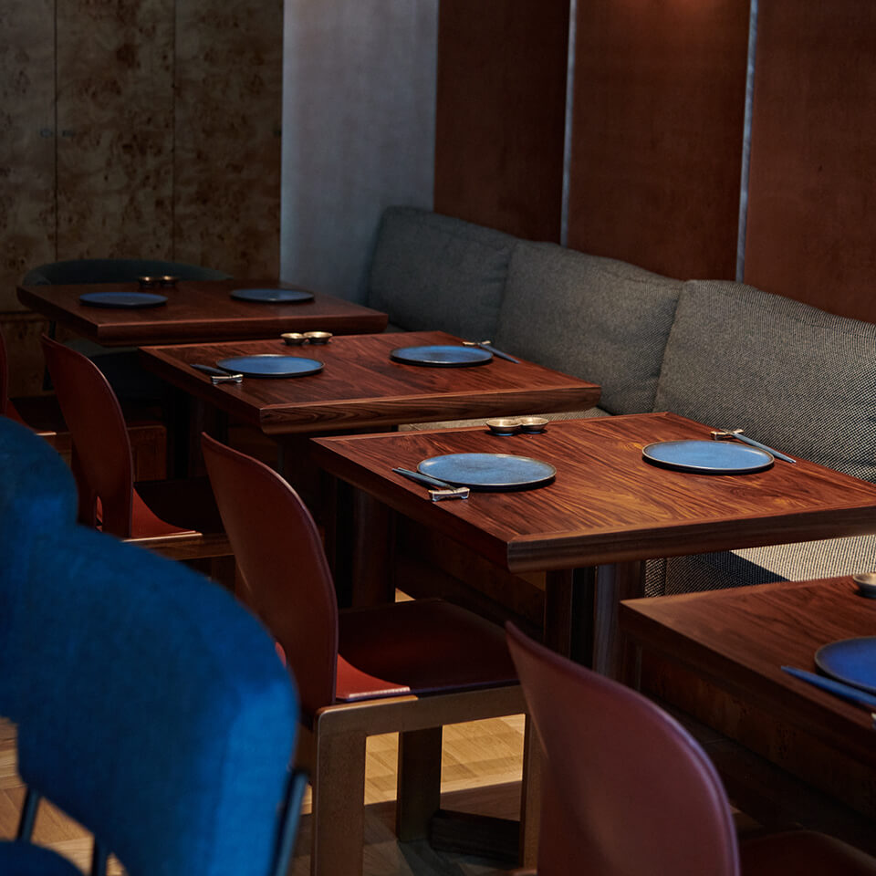 Wooden tables with blue plates and chairs at Uchi restaurant in Dubai